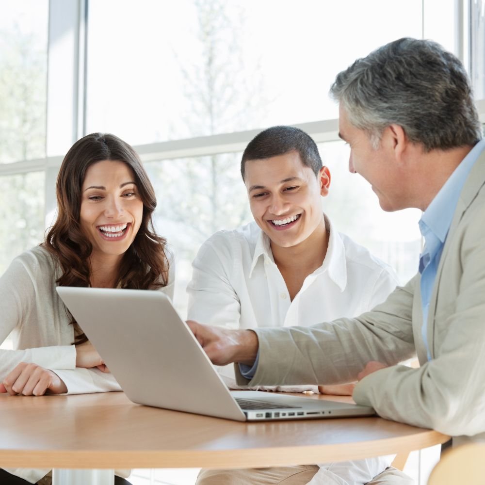 Smiling colleagues collaborating at a laptop.