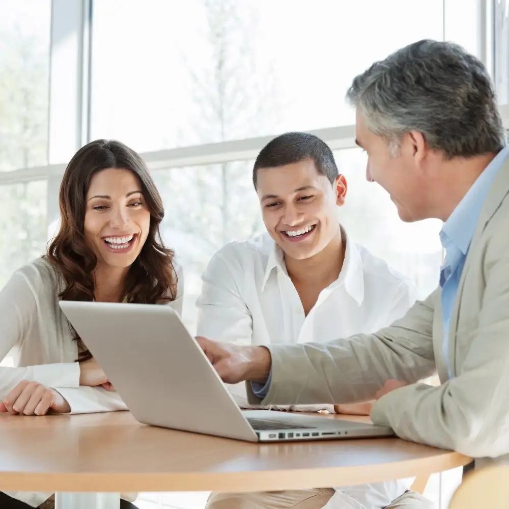Smiling colleagues collaborating at a laptop.
